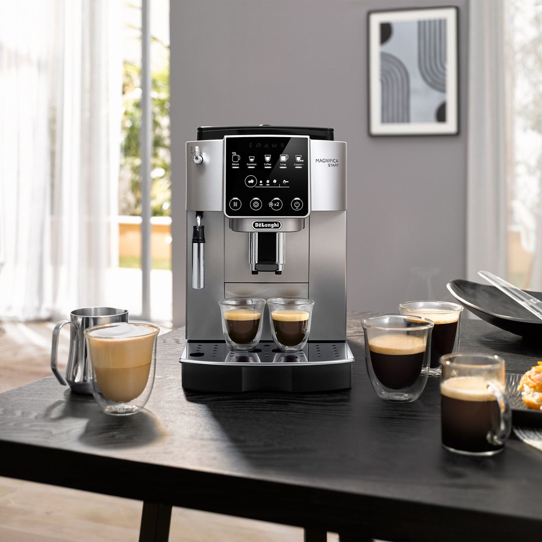 De'Longhi Magnifica Start coffee machine on a table with coffee cups