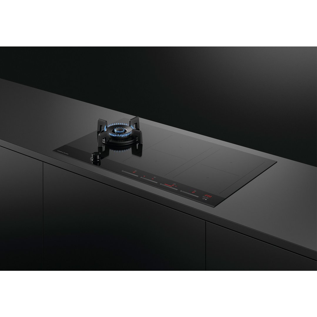 Hybrid cooktop with gas burner and induction zones built into a dark kitchen counter