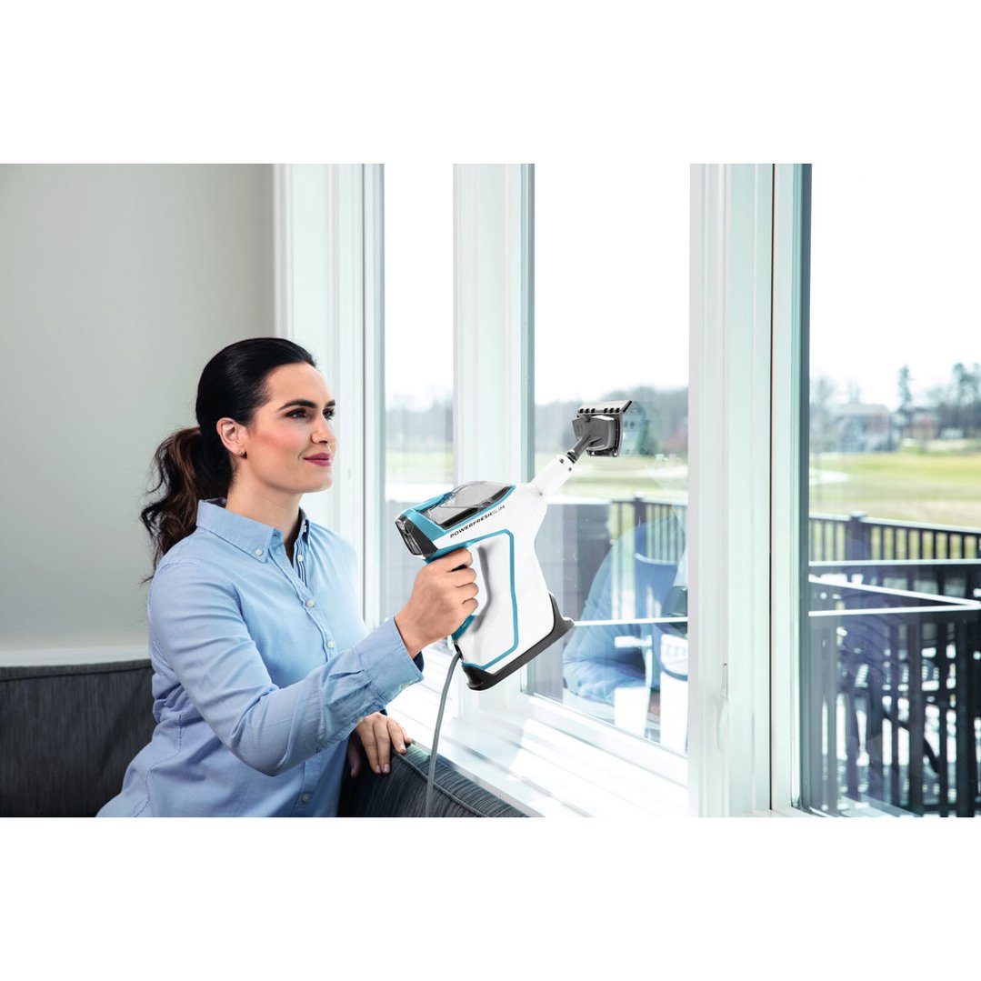 Woman cleaning a window with a BISSELL PowerFresh Slim Steam Mop