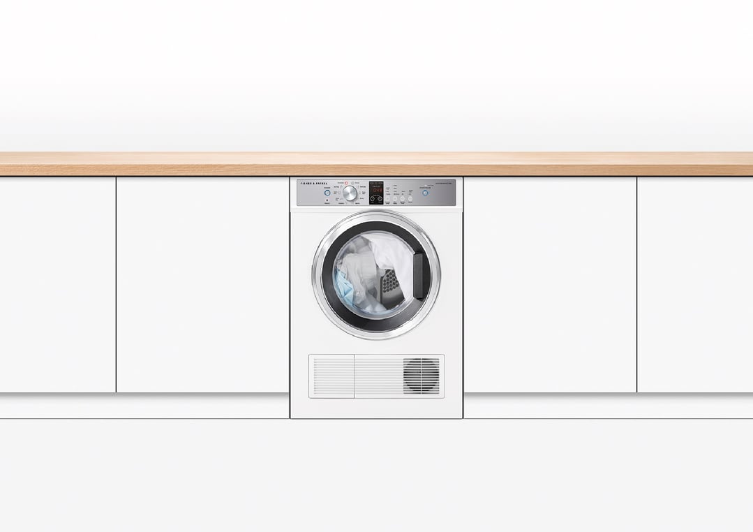 White vented dryer built into white cabinetry with a light wood countertop