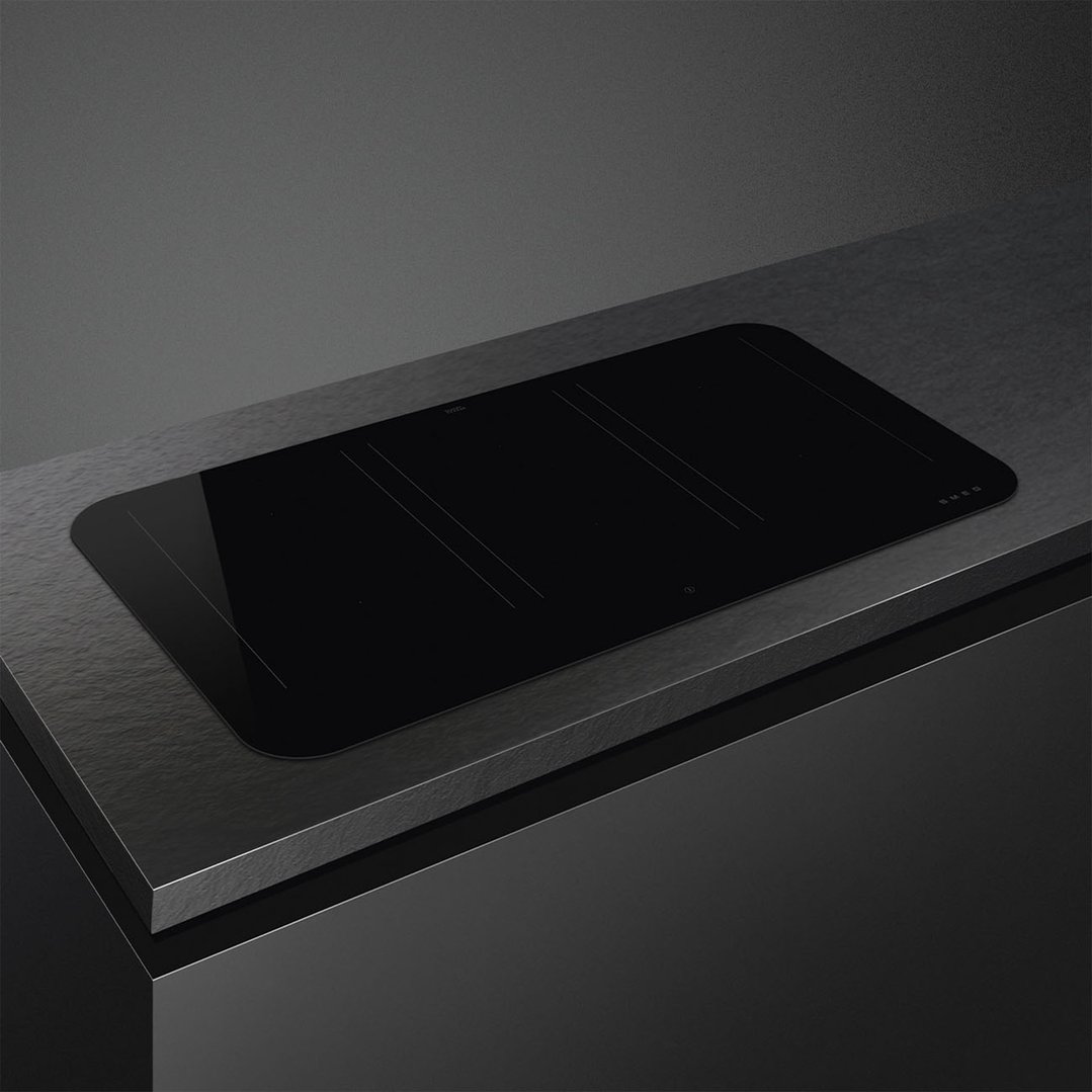 Black induction cooktop built into a dark countertop in a modern kitchen