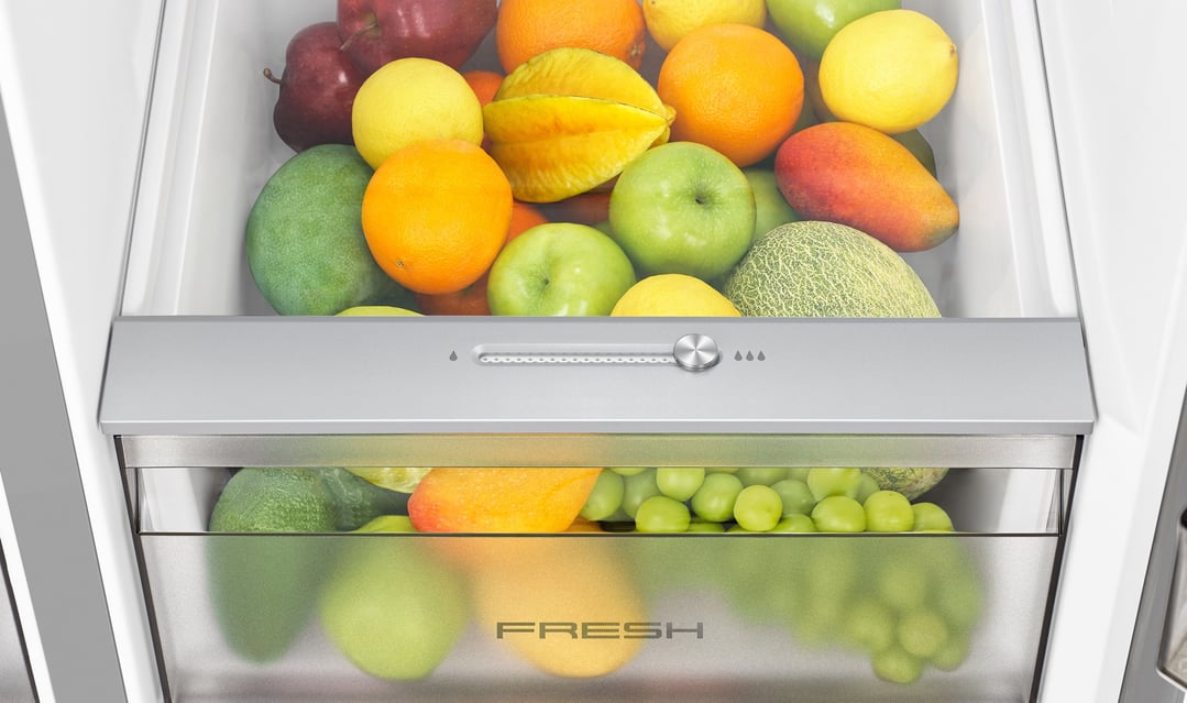 Close up of a fridge drawer filled with fresh fruit and vegetables