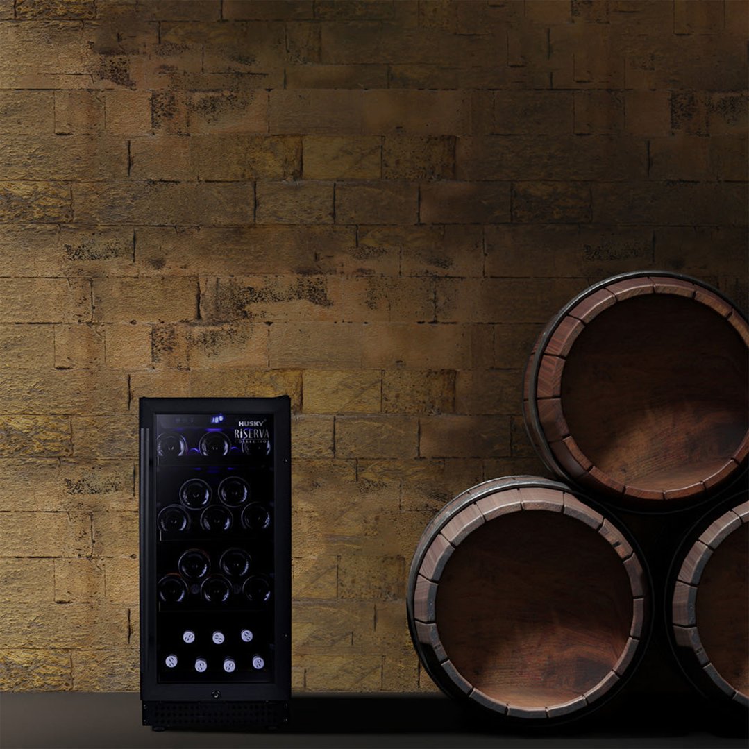 Black wine fridge with bottles in a cellar-like setting with barrels
