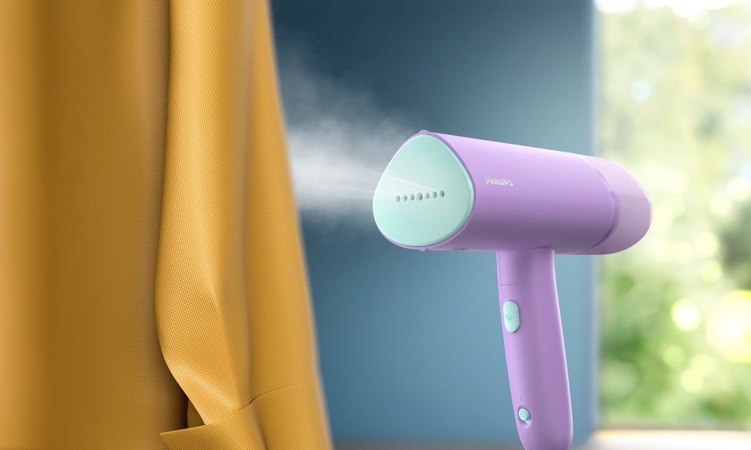 Purple handheld garment steamer steaming a yellow fabric in a room