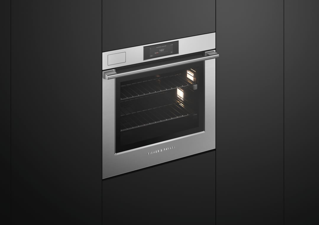 Stainless steel built-in oven with illuminated interior and digital display in a dark kitchen