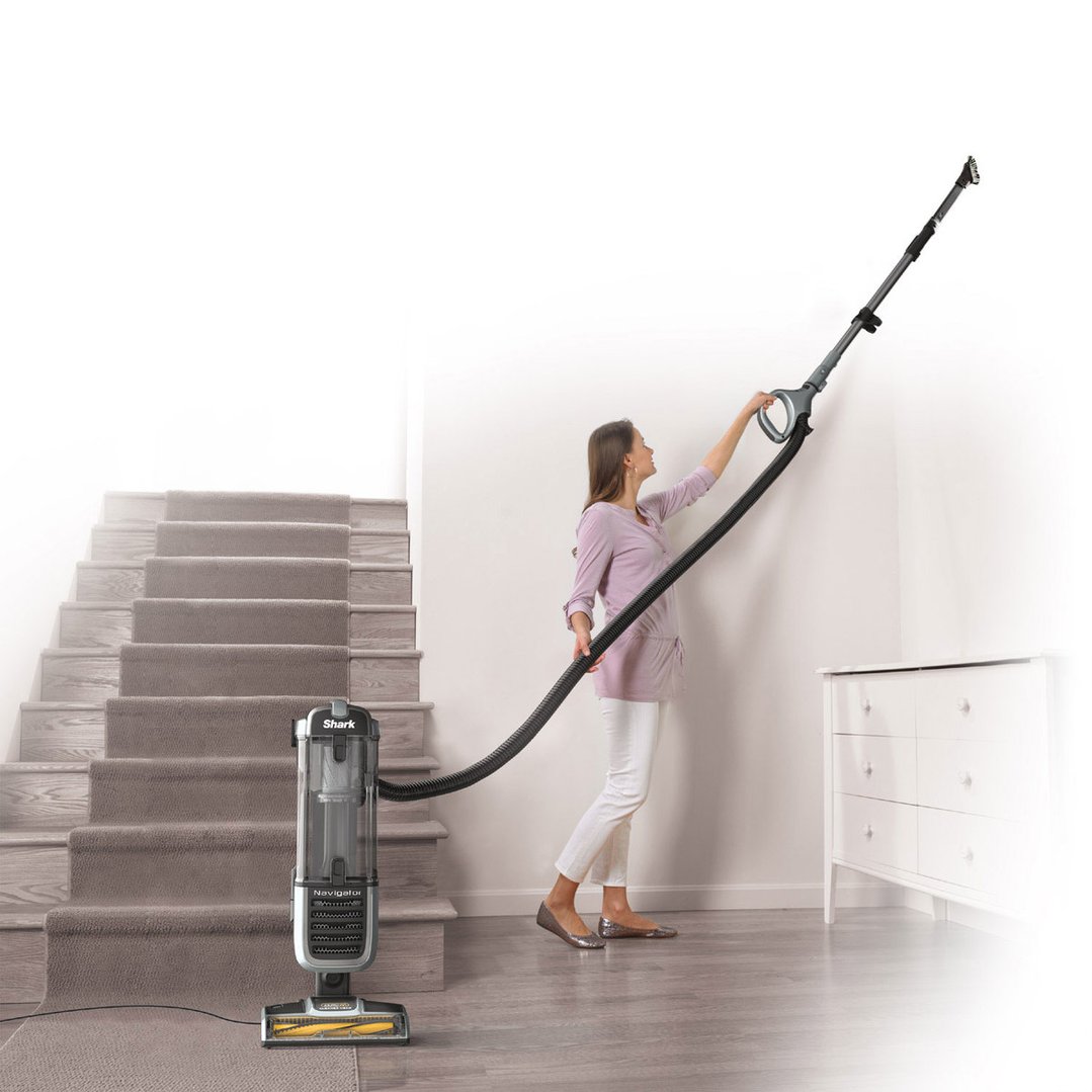 Woman using a Shark Navigator vacuum cleaner to clean a high wall