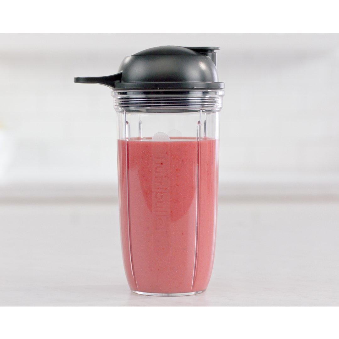 Nutribullet blender cup with a pink smoothie on a white countertop