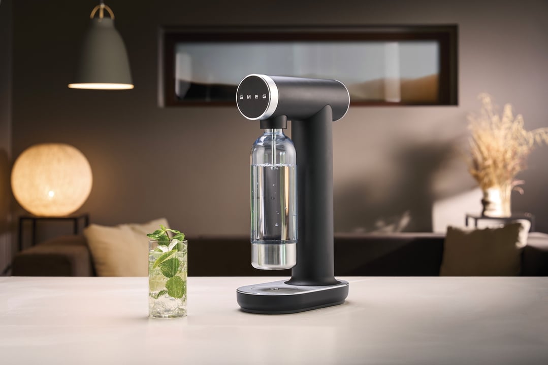 Black Smeg soda maker on a counter with a drink in a living room