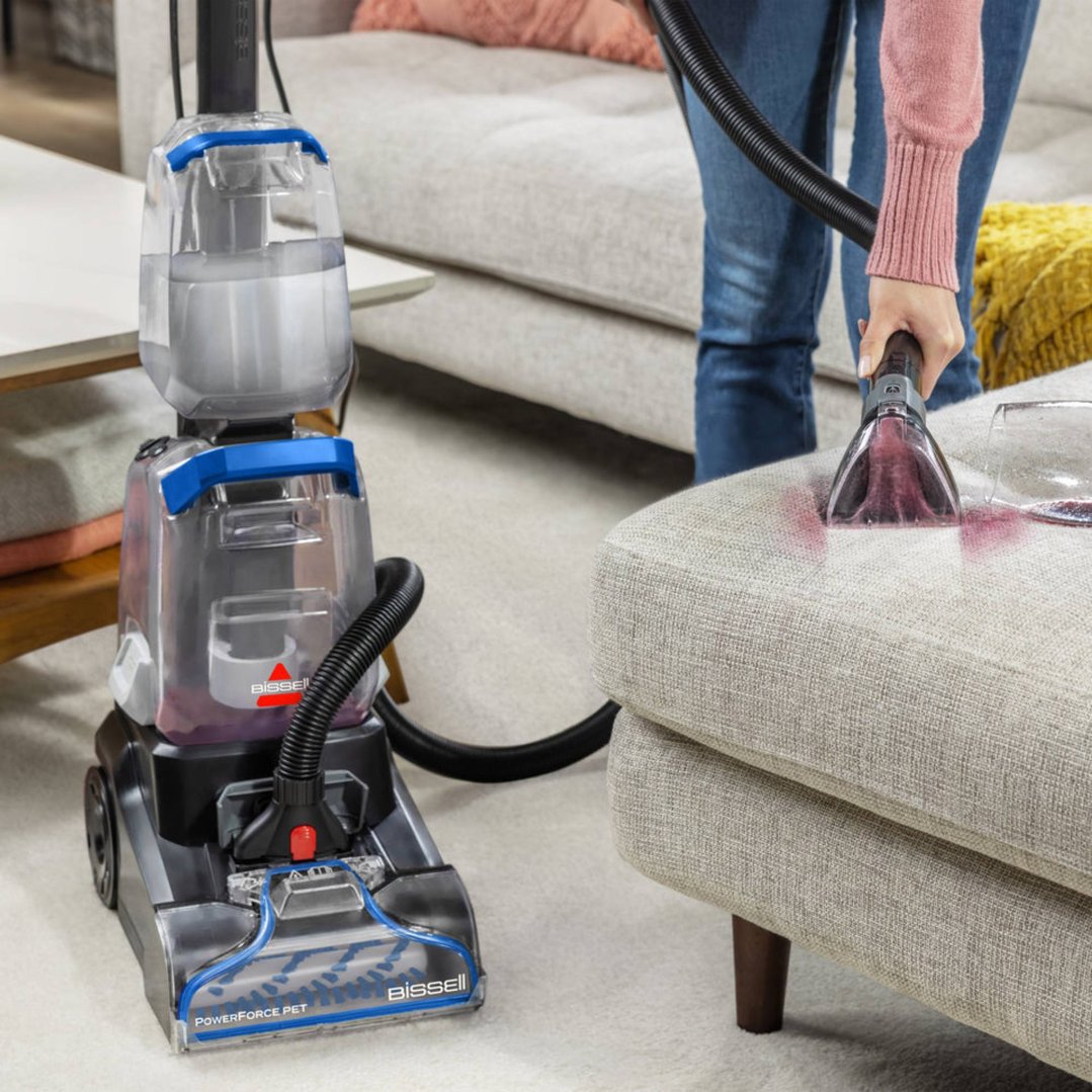 Woman cleaning a red wine stain from a sofa with a carpet and upholstery cleaner