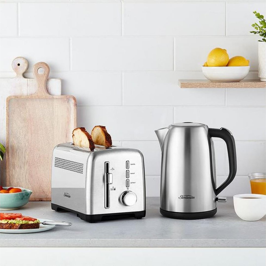 Stainless steel kettle and toaster on a kitchen counter with breakfast items