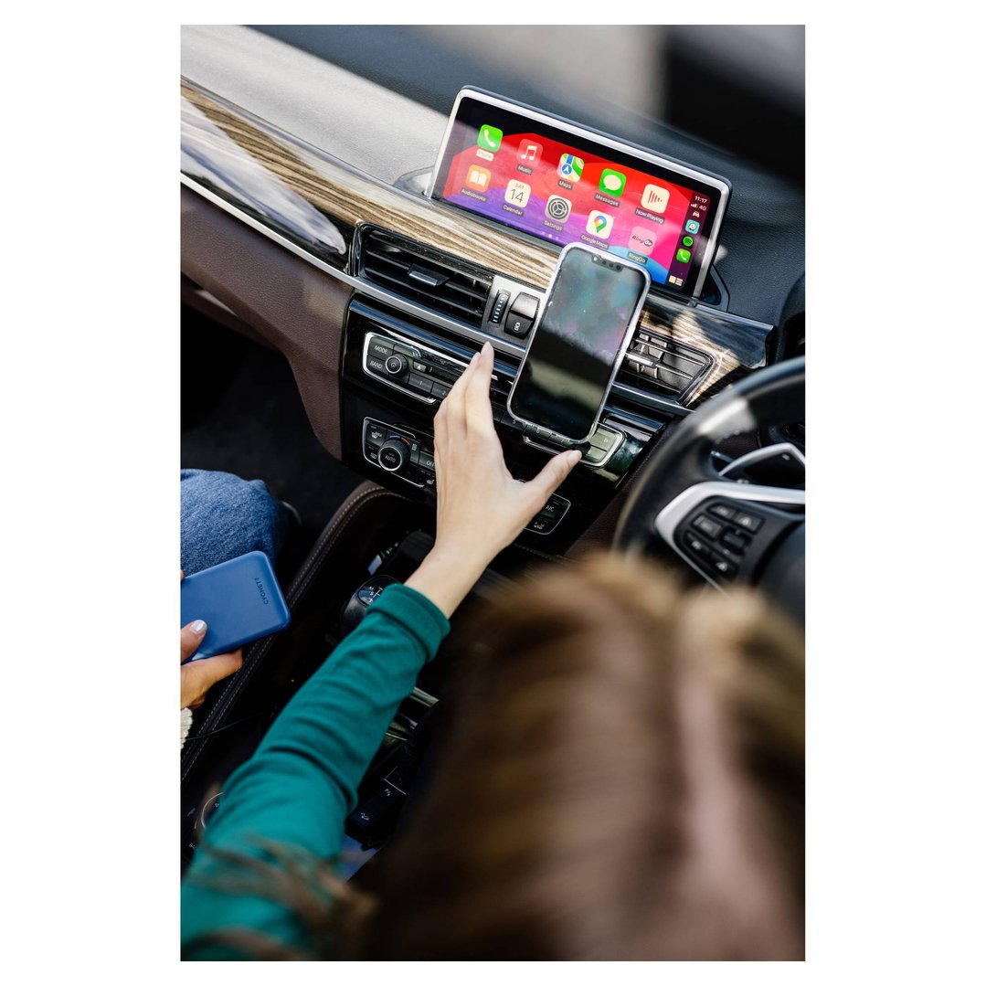 Woman's hand adjusting a phone on a car mount with a carplay adapter screen