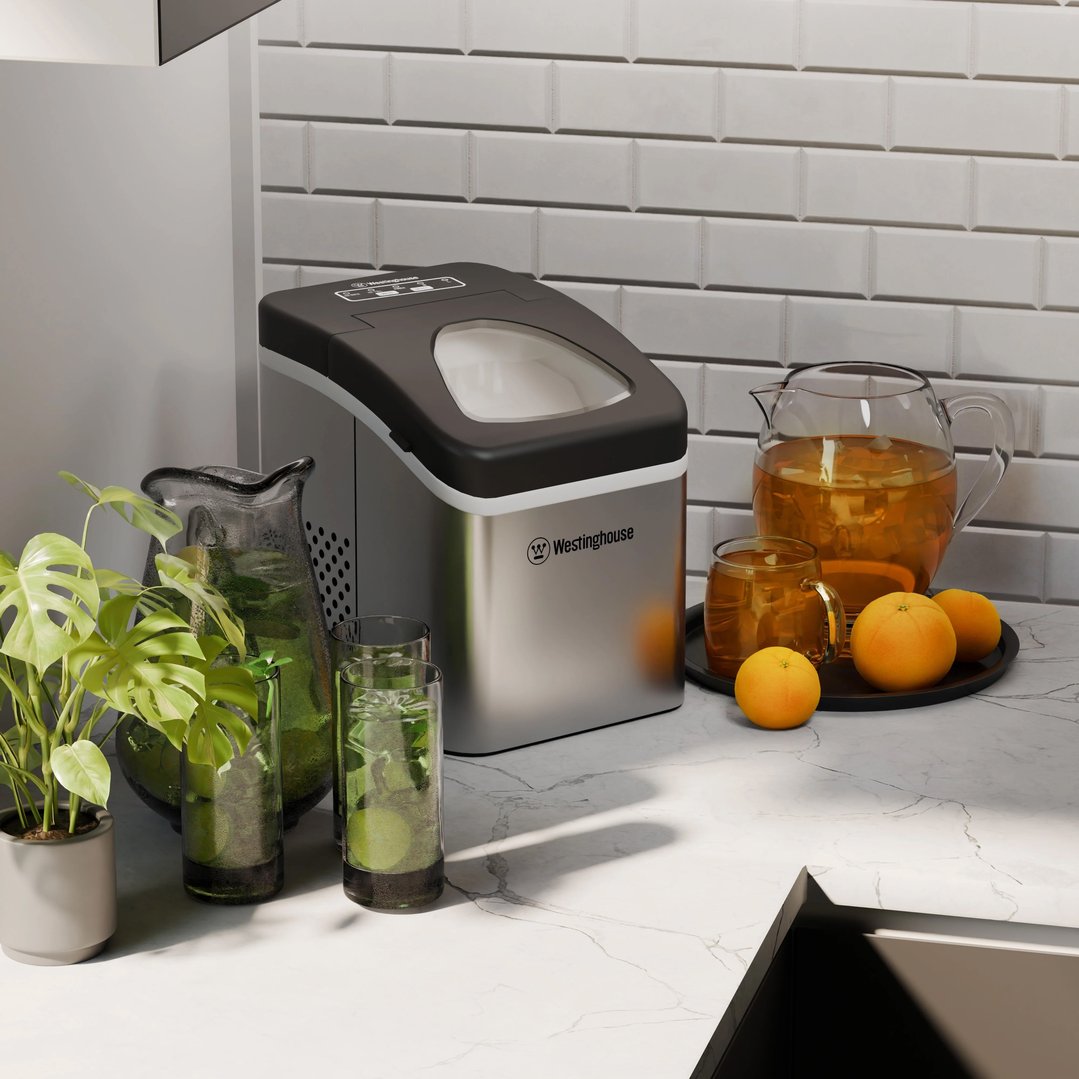 Ice maker on a white marble countertop with drinks and oranges