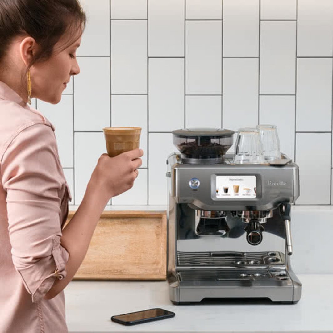 Woman holding a coffee cup next to a Breville coffee machine