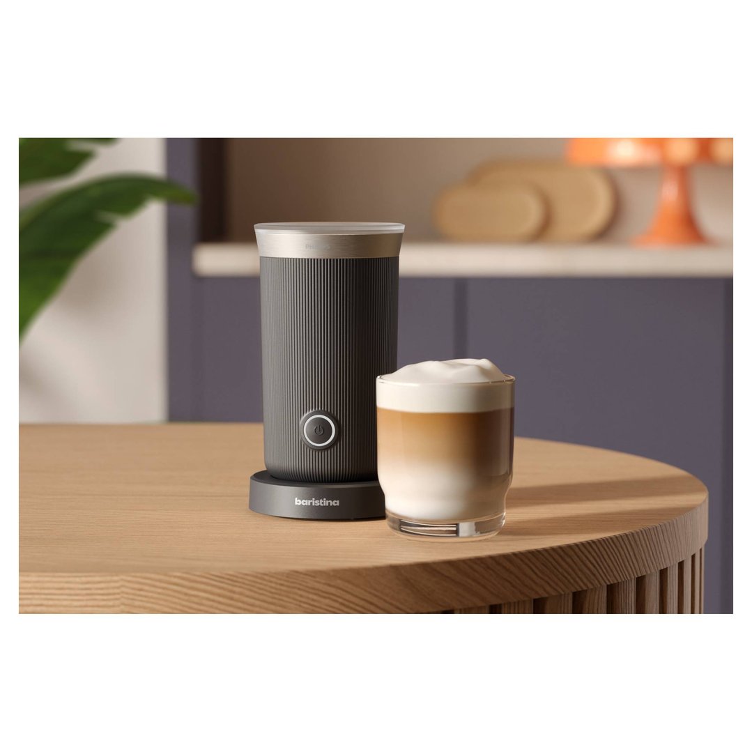 Baristina milk frother and a glass of latte on a wooden table
