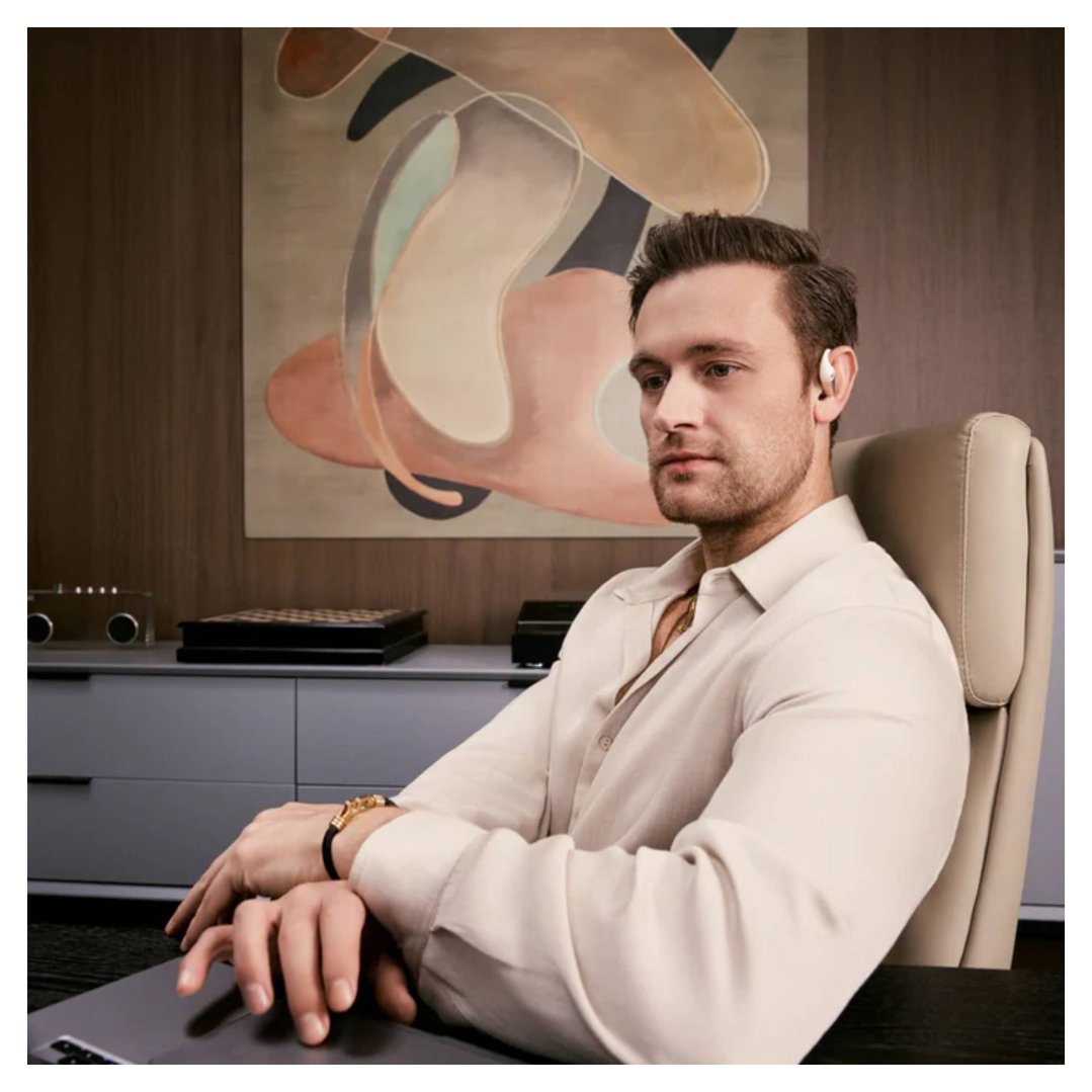 Man wearing OpenFit Pro wireless open-ear headphones while sitting at a desk