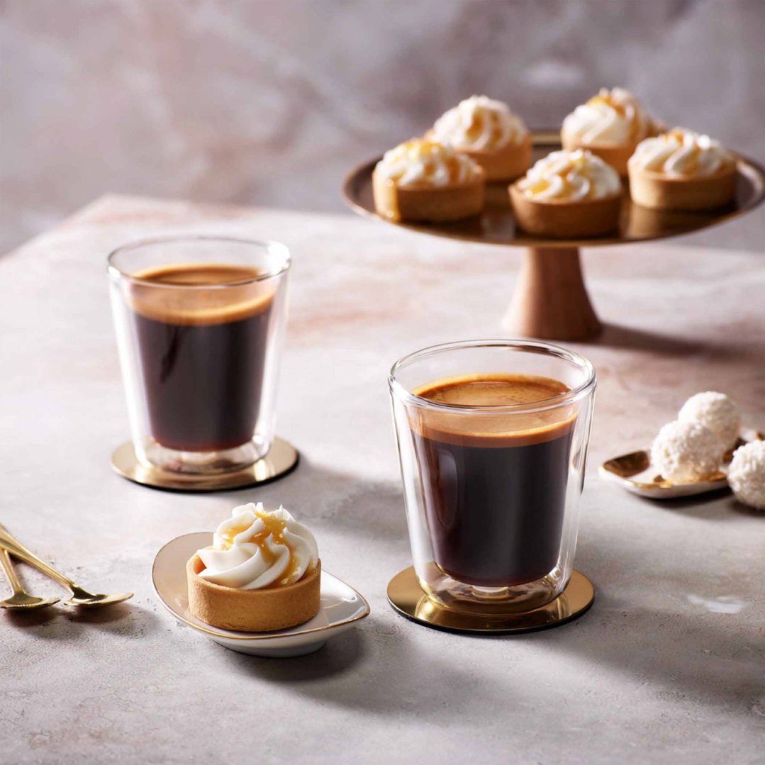Two Dual Wall Glasses Latte with desserts on a light-colored surface