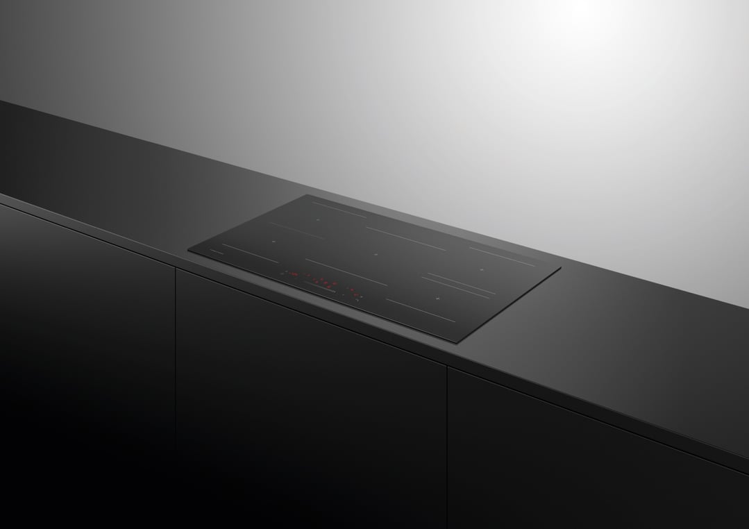 Black induction cooktop built into a dark kitchen counter with cabinets below