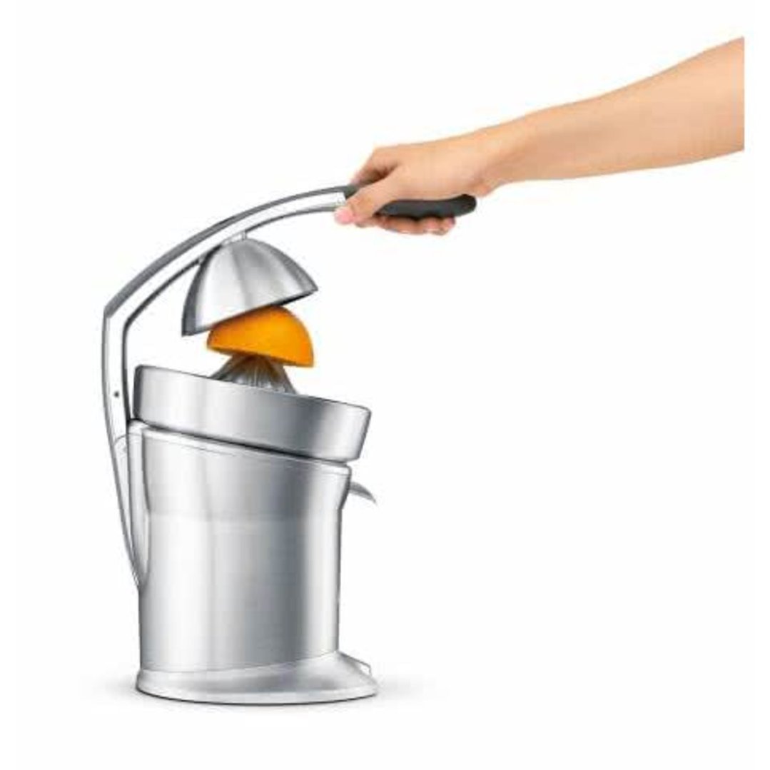 Hand pressing an orange half in a silver citrus press on a white background
