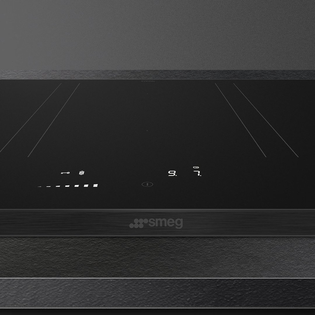 Close up of a black induction cooktop with digital controls in a kitchen