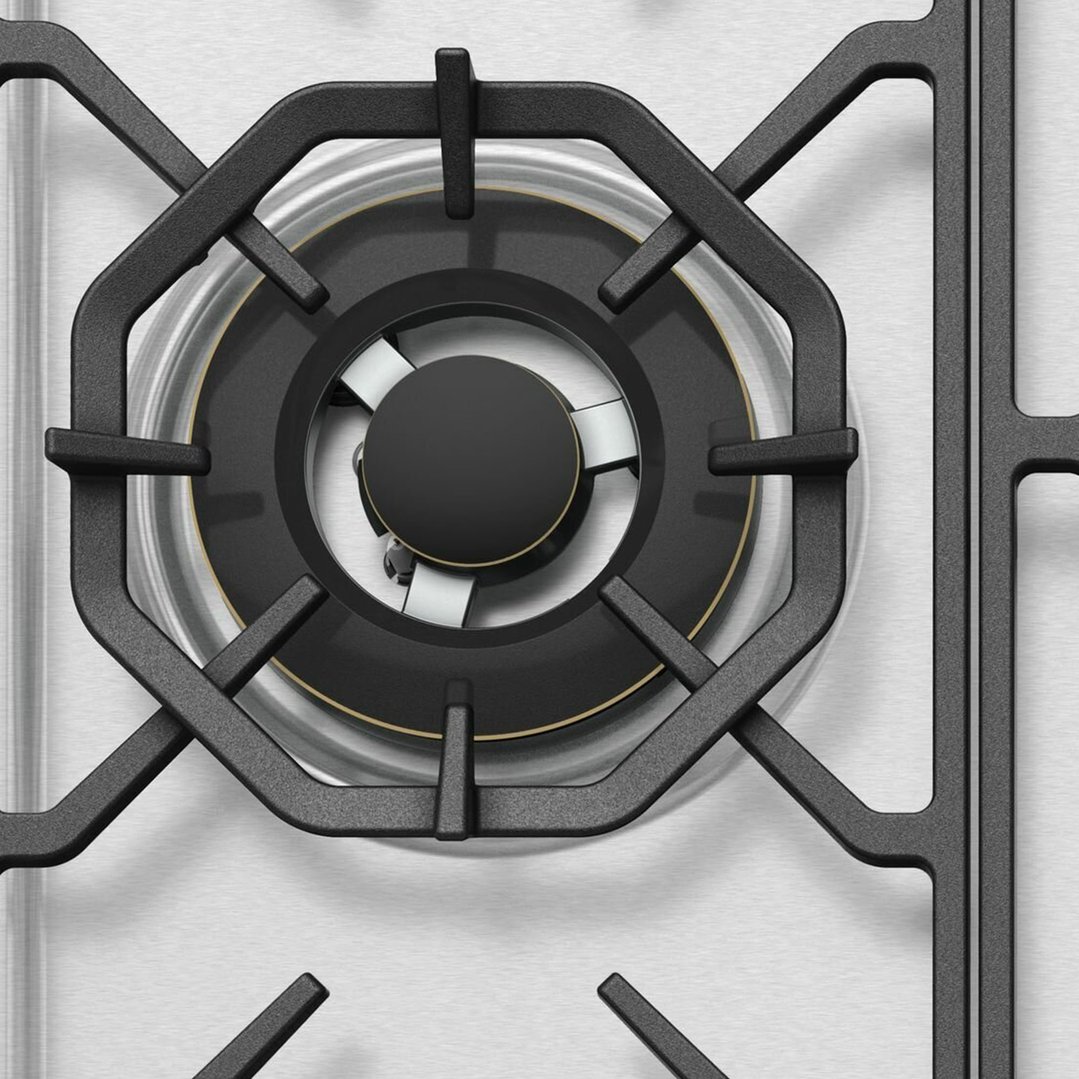 Close up of a gas cooktop burner and grates on a stainless steel surface