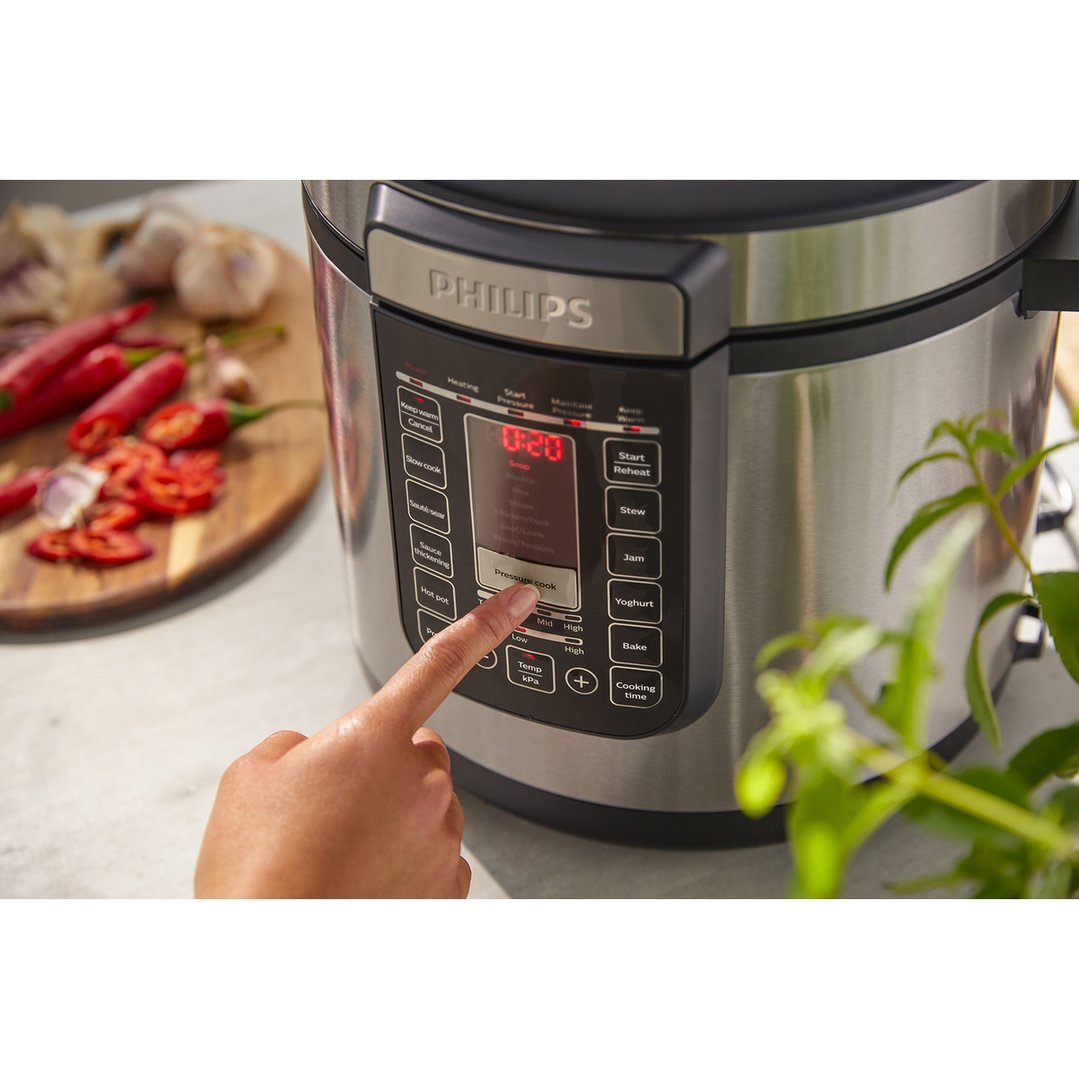 Hand pressing a button on the Philips All-in-One Cooker control panel