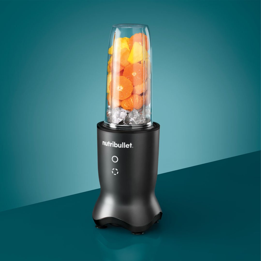 NUTRiBULLET Ultra 1000 blender with fruit and ice on a teal surface