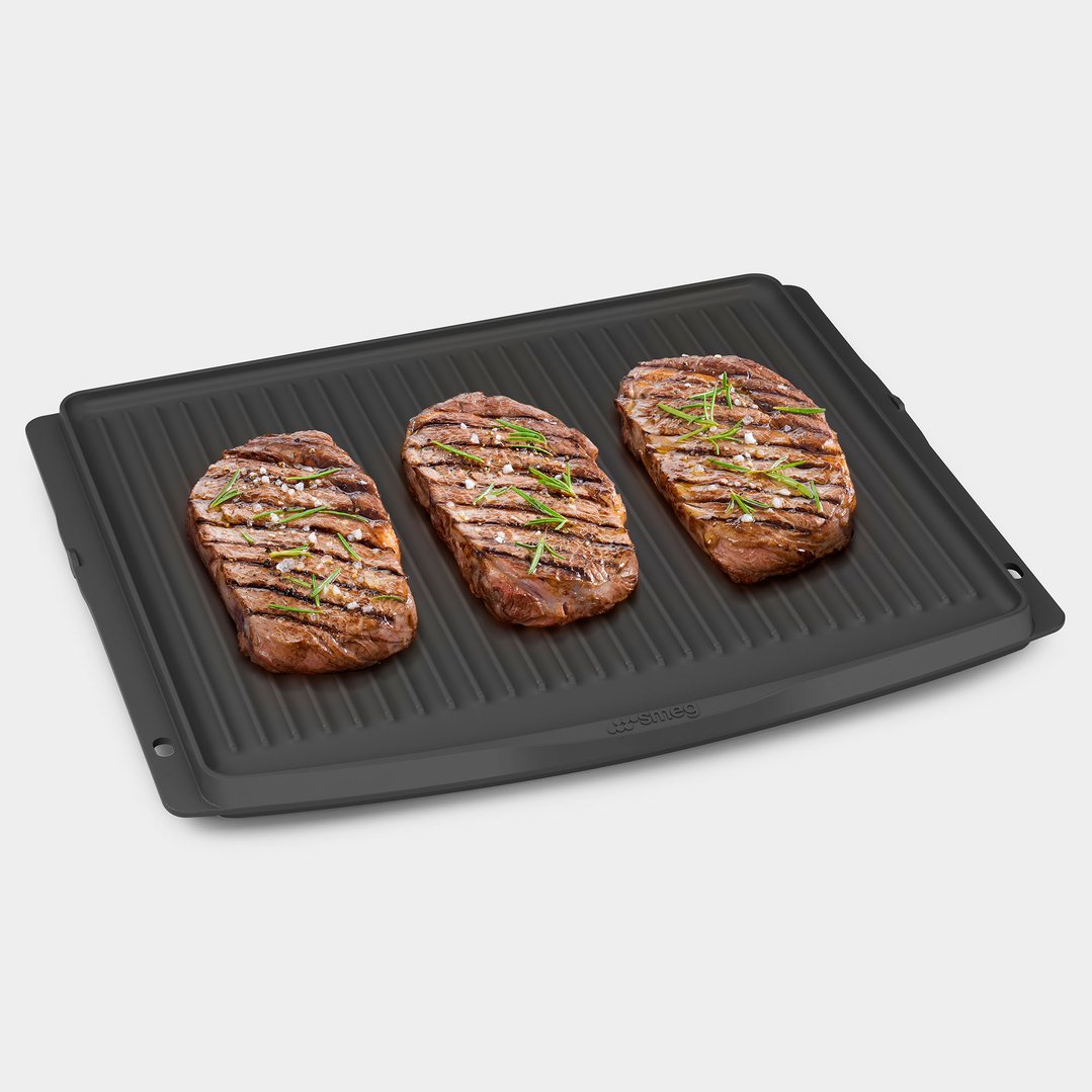 Three grilled steaks with seasoning on a black BBQ tray