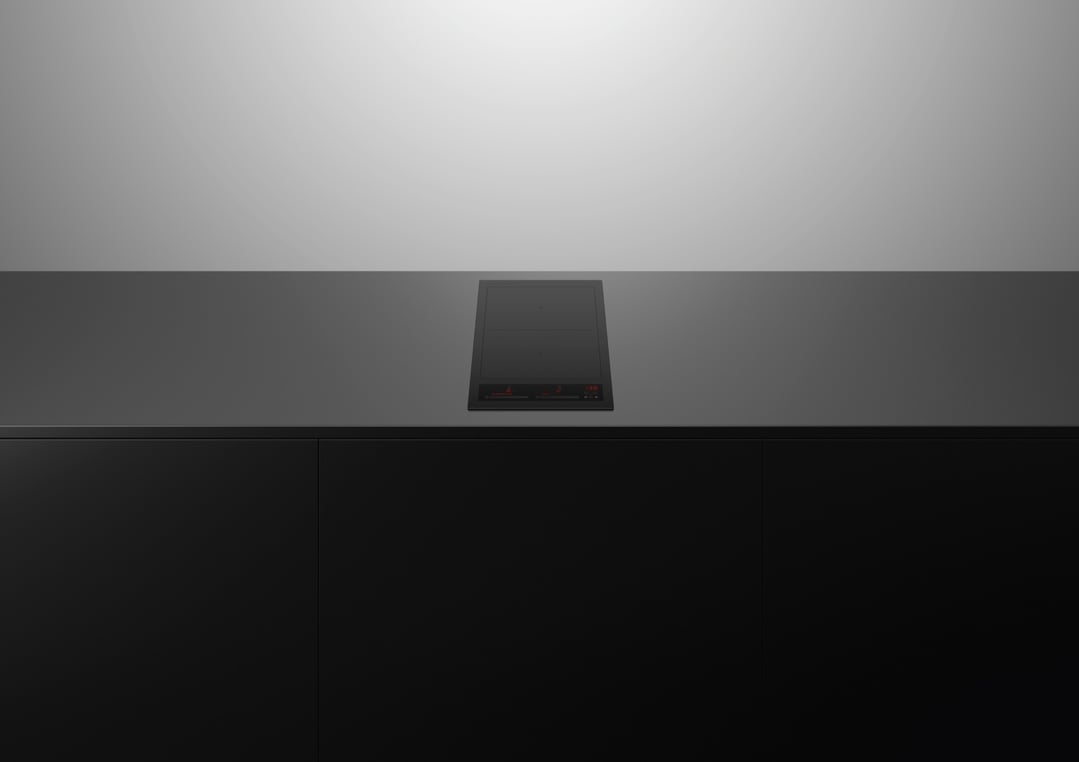 Black induction cooktop built into a dark countertop with dark cabinetry below