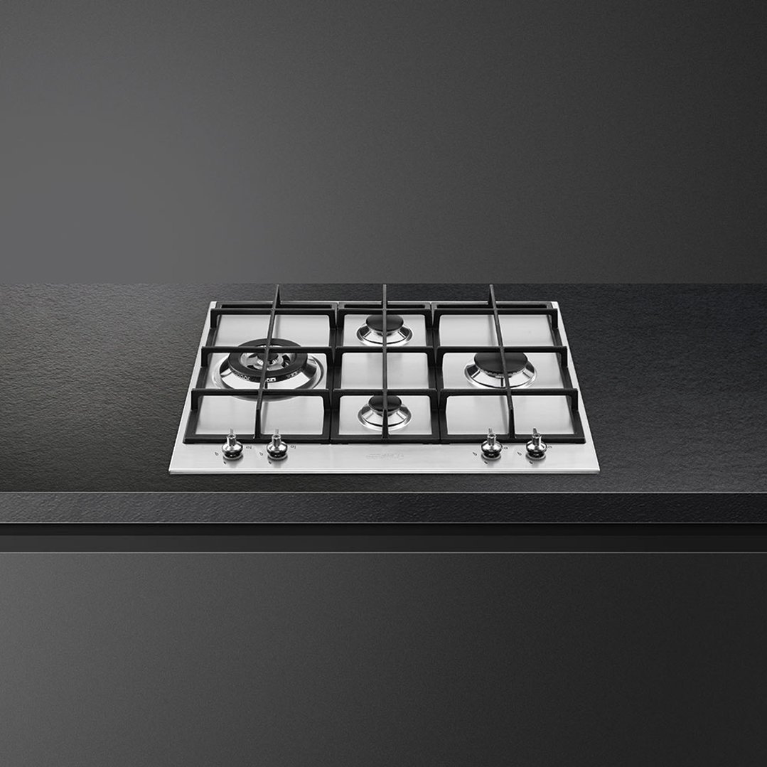A stainless steel gas cooktop with five burners installed in a dark countertop