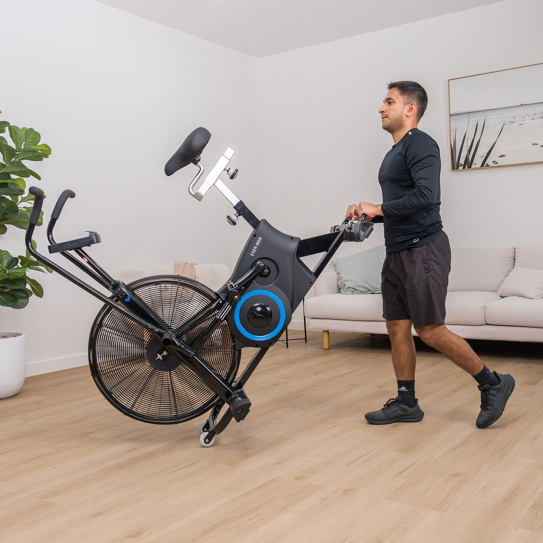 Man moving a black exercise air bike in a living room