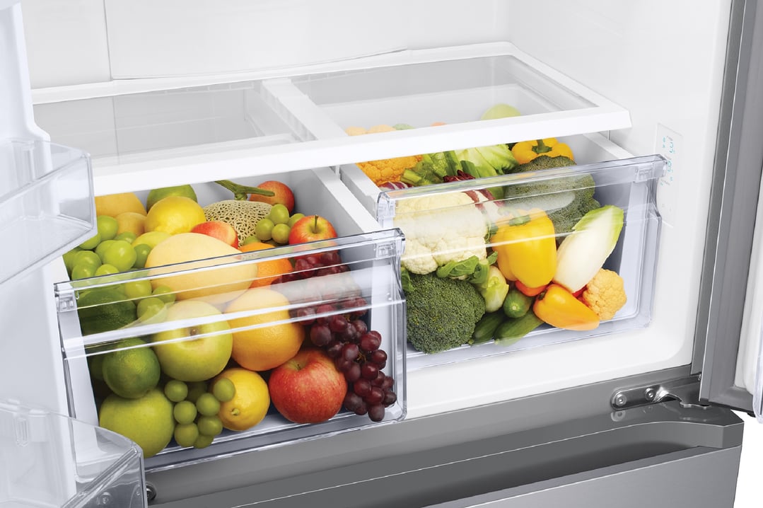 Open French door refrigerator showing fresh fruits and vegetables in crisper drawers