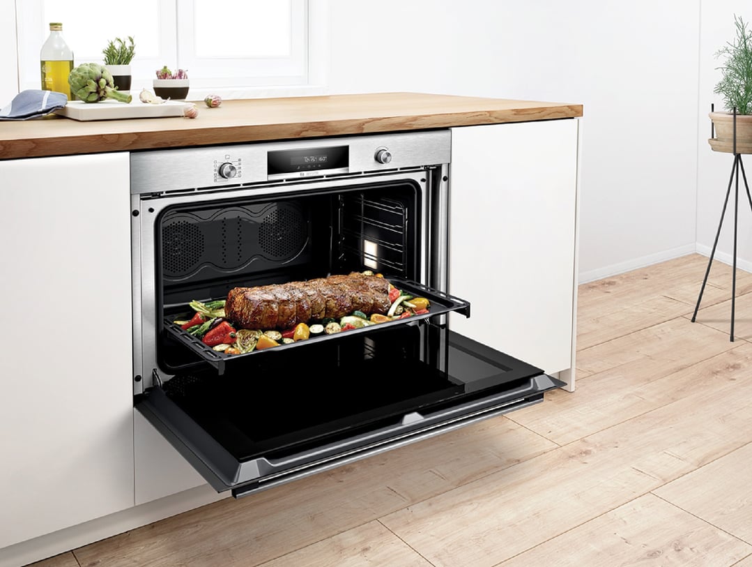 Built-in oven with door open, food cooking inside, in a modern kitchen