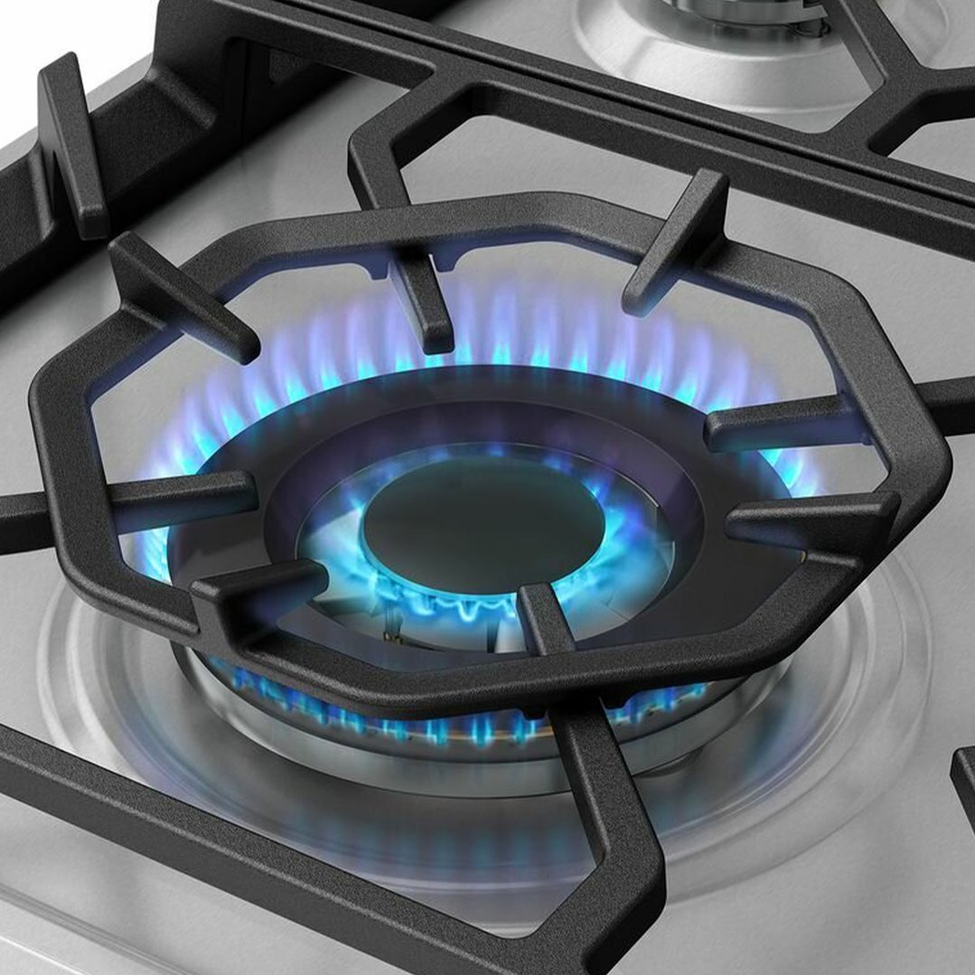 Close up of a gas cooktop burner with blue flames ignited