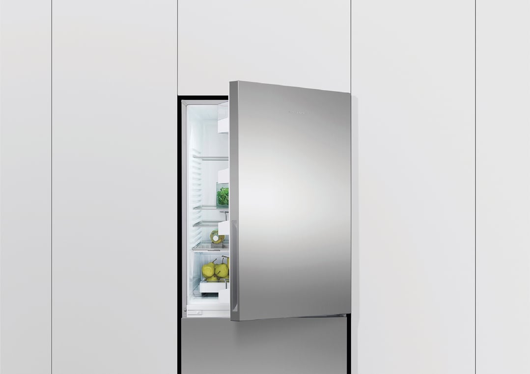 Stainless steel refrigerator freezer with door open showing fresh produce inside