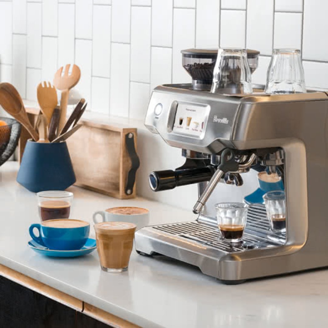 Breville Barista Touch coffee machine on a kitchen counter with various coffee cups