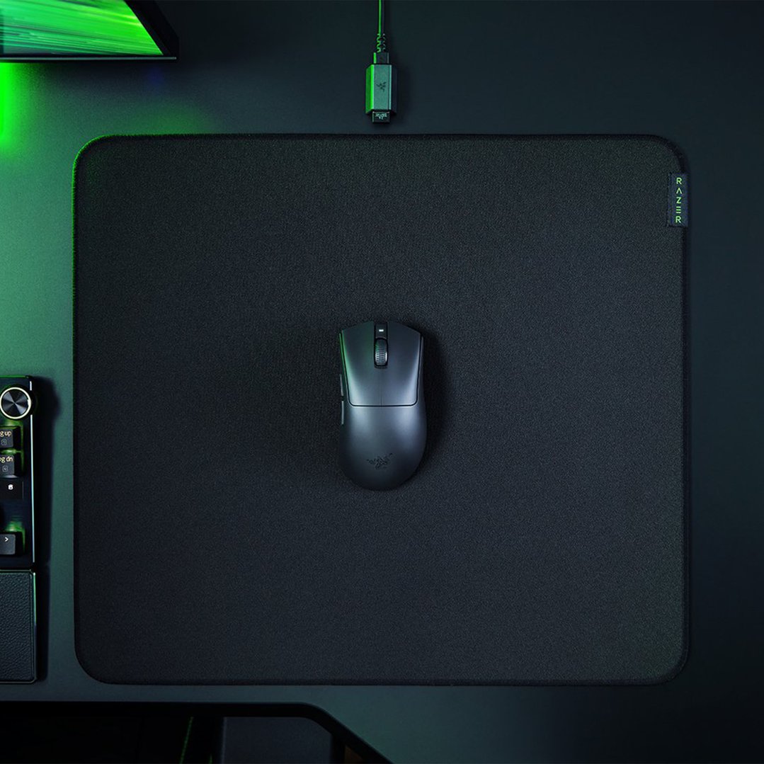 A black gaming mouse on a black mouse pad with green lighting
