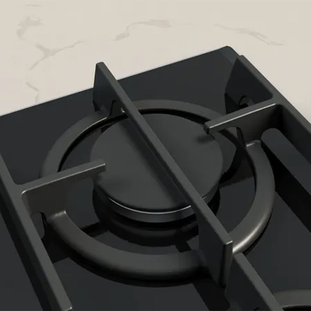 Close up of a black cooktop burner on a white marble countertop