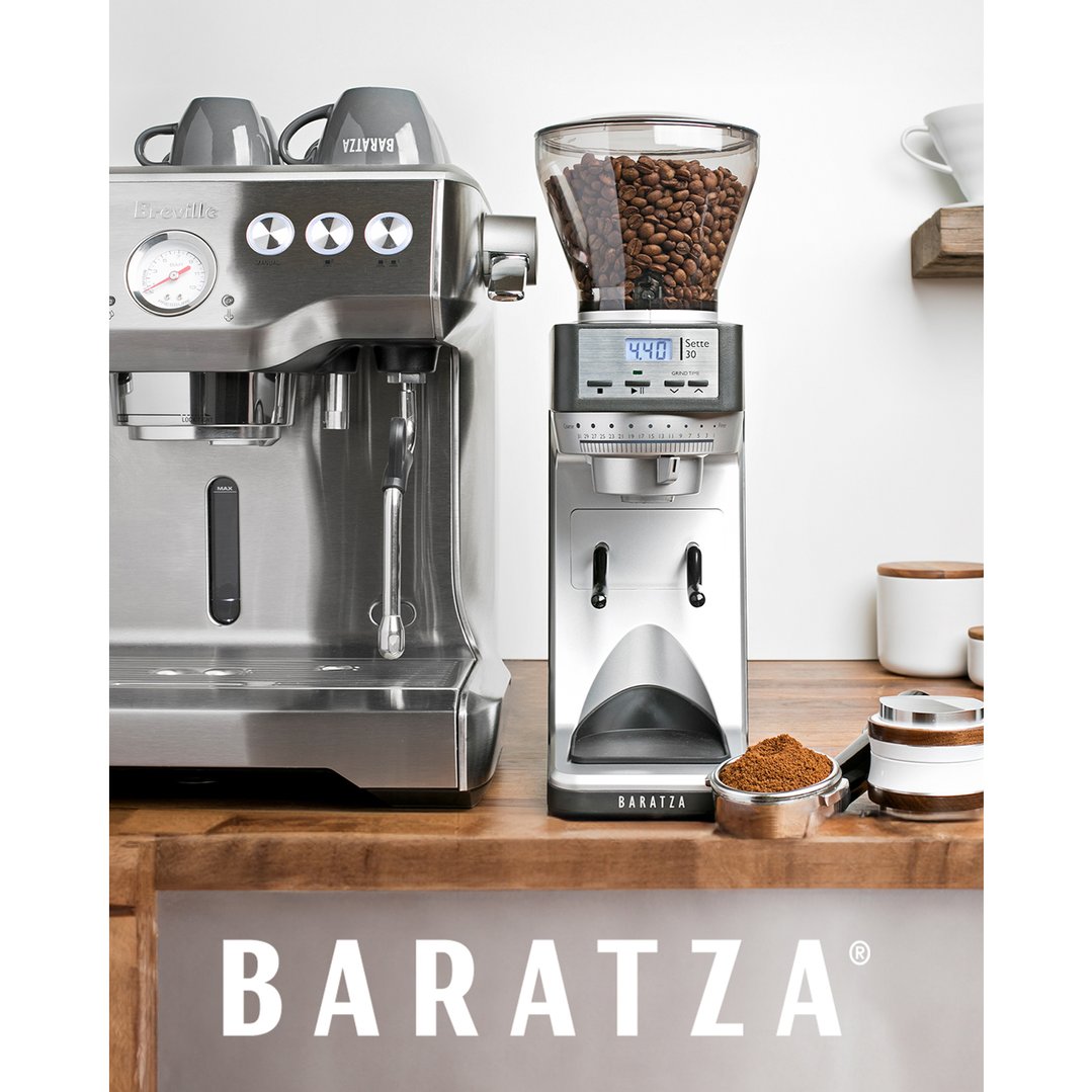 Coffee grinder and espresso machine on a wooden counter with coffee cups