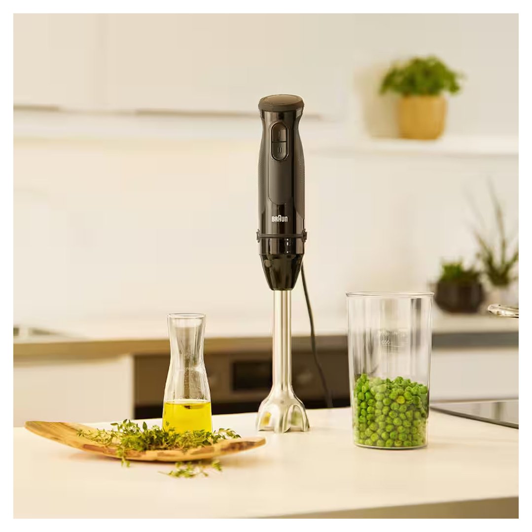 Black Braun hand blender on a kitchen counter with peas and olive oil