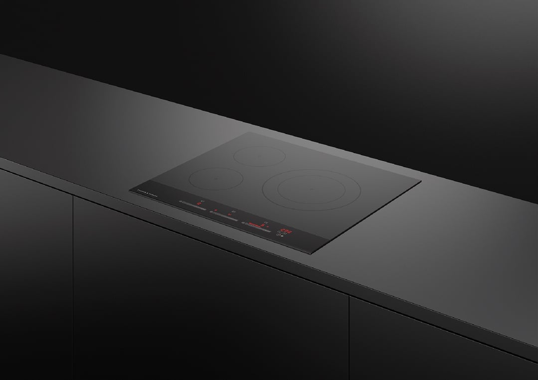 Black 3-zone induction cooktop built into a dark kitchen countertop