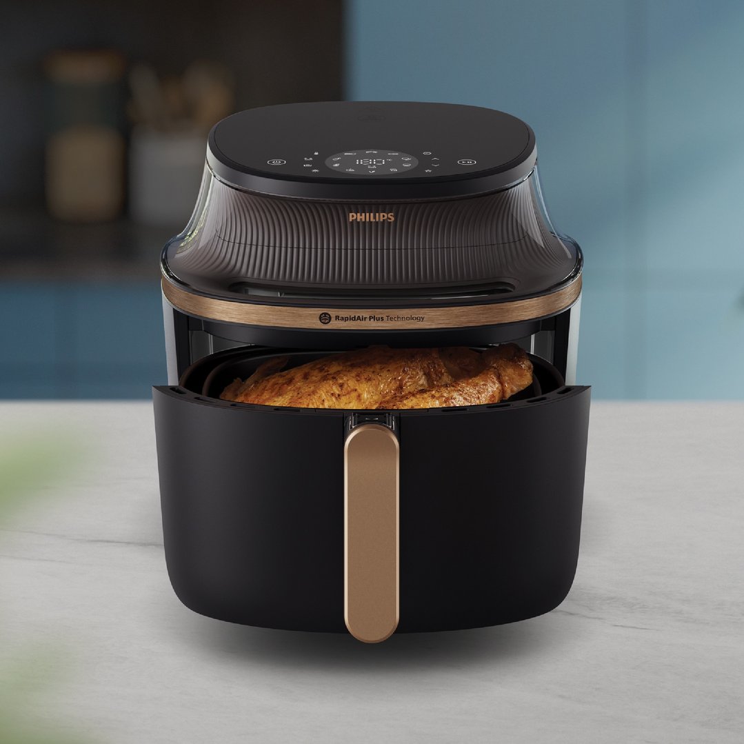 Philips airfryer with a cooked chicken inside, on a kitchen counter