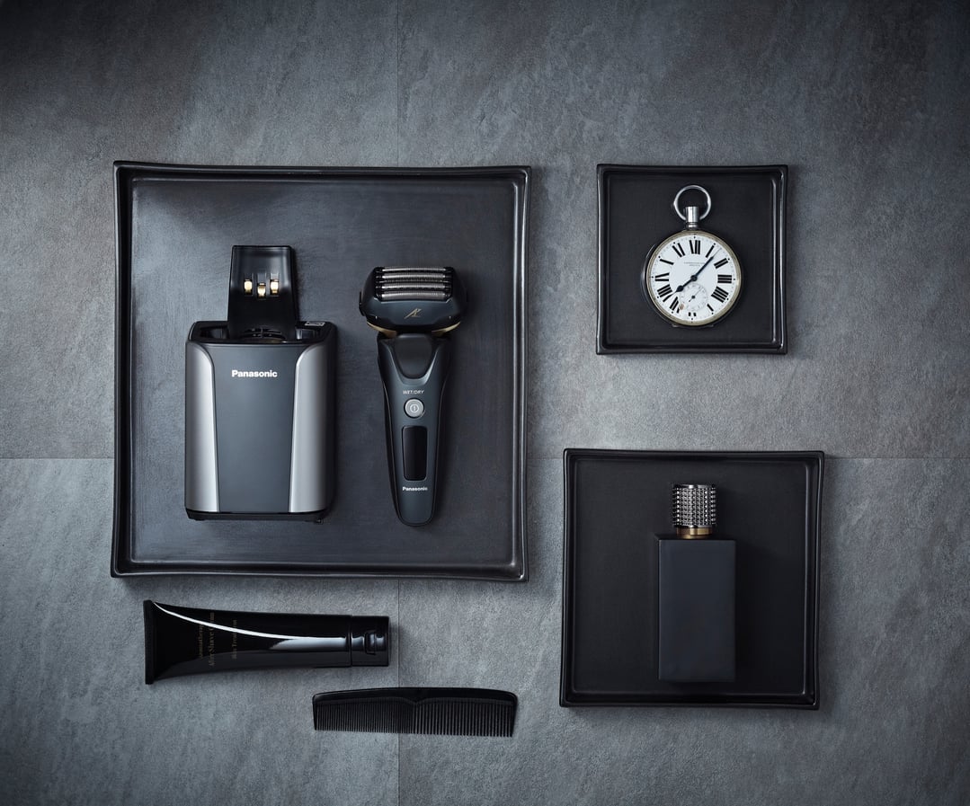 Panasonic shaver and accessories on black trays on a dark grey surface