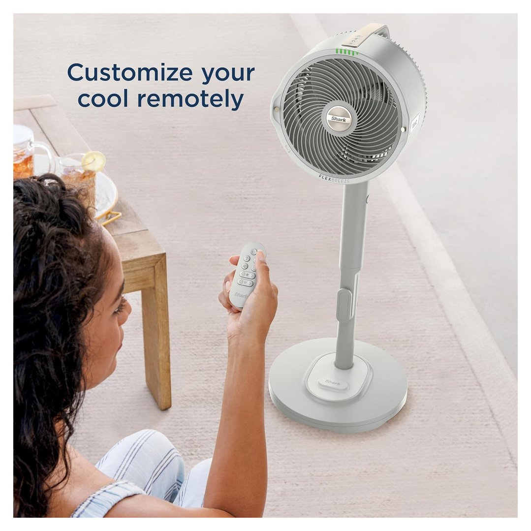 Woman sitting on floor, using remote control for a white pedestal fan