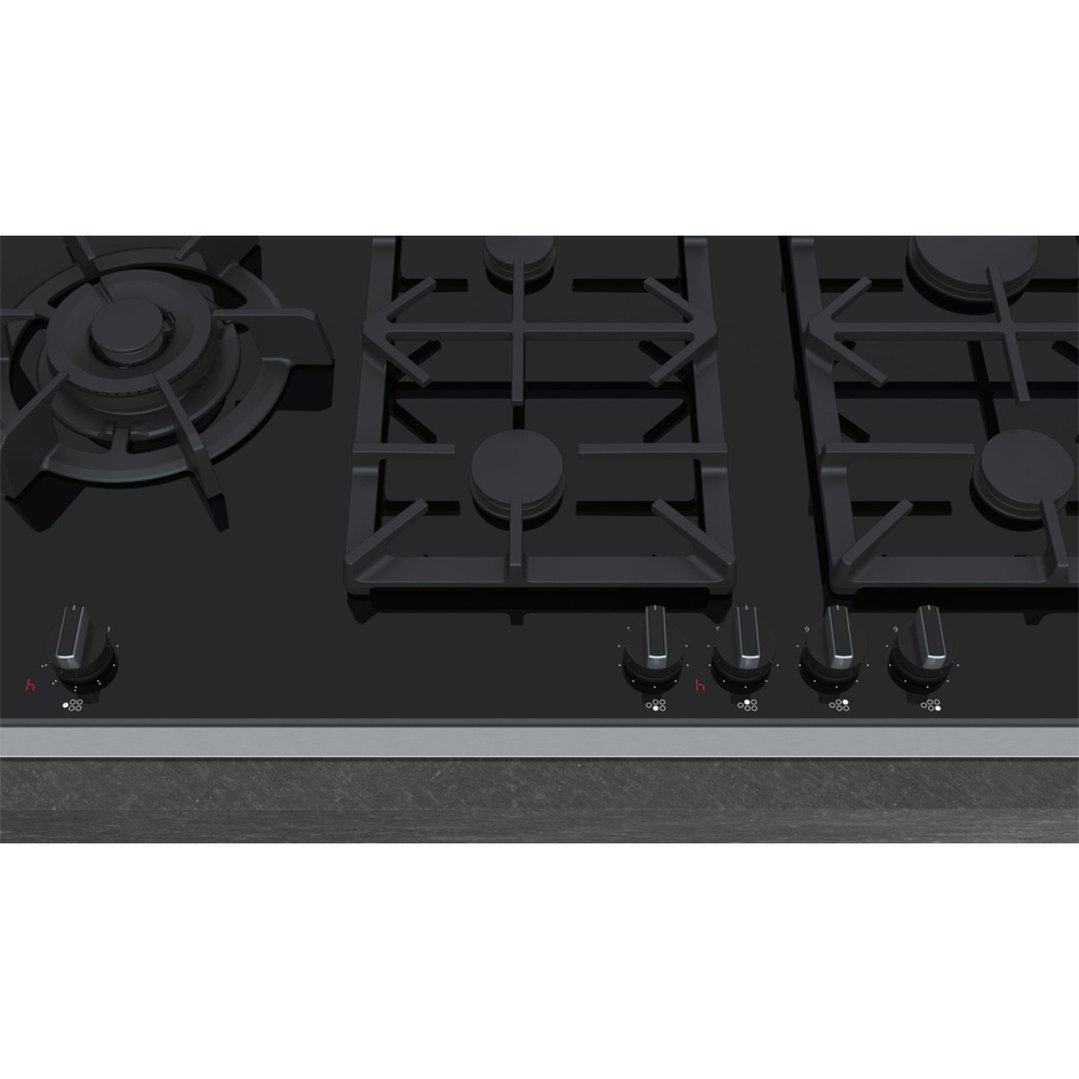 Close up of a black gas cooktop with five burners and control knobs