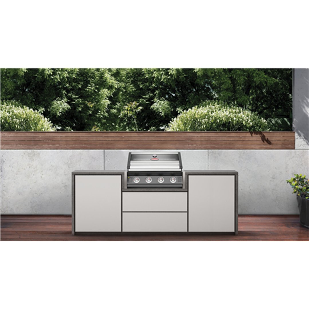 Built-in 4 burner barbeque in an outdoor kitchen setting with greenery