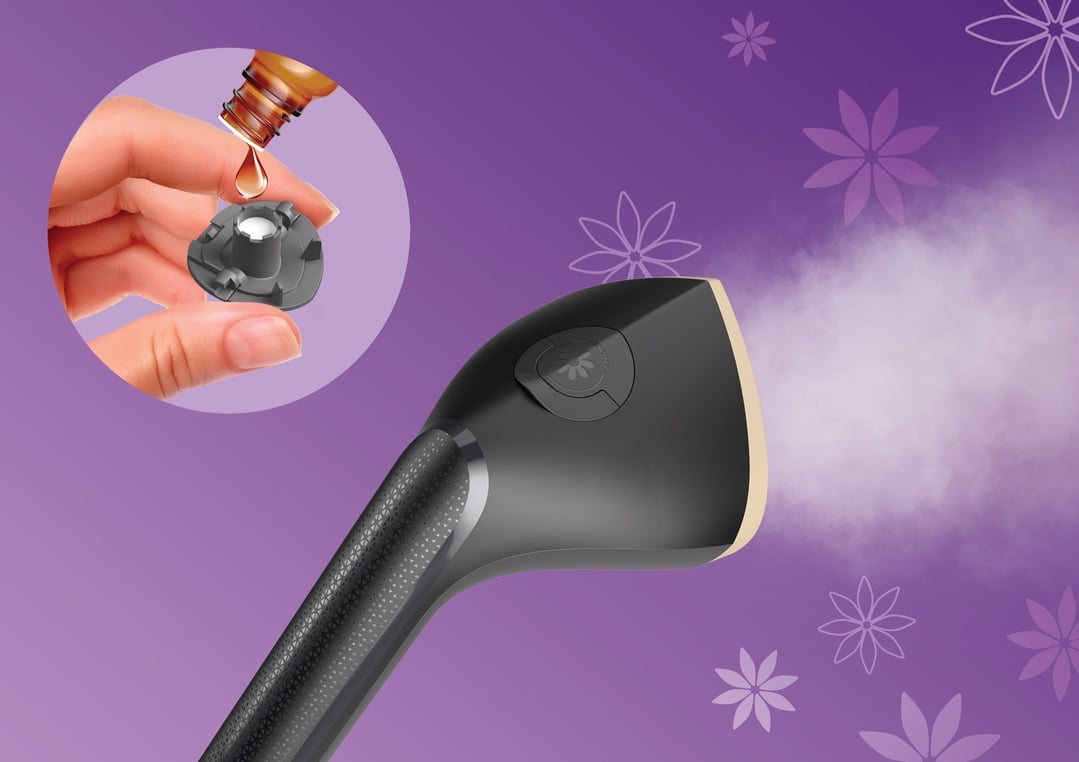 Hand adding essential oil to the fragrance cap of a garment steamer