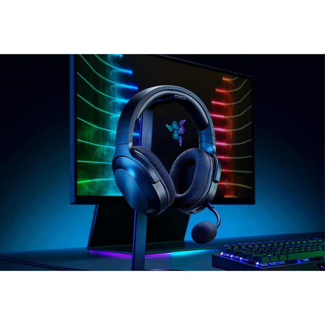 Black wireless headset on a stand with a monitor and keyboard in the background