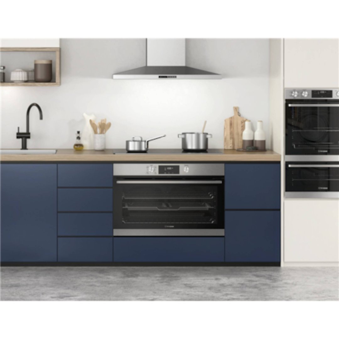 Cooktop and ovens in a modern kitchen with blue cabinets and wooden countertop