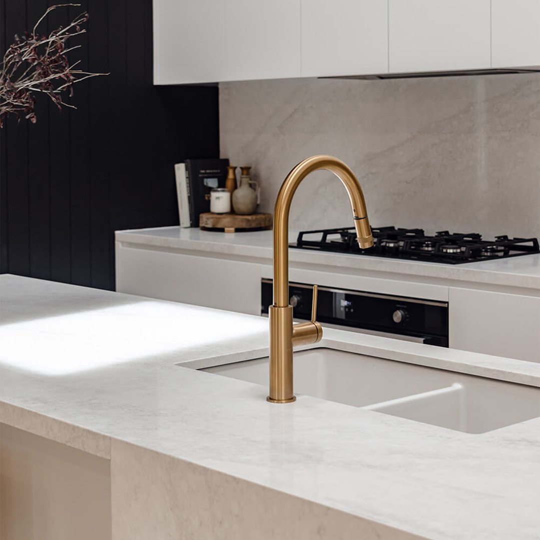 A gold faucet over a double matte white sink in a modern kitchen