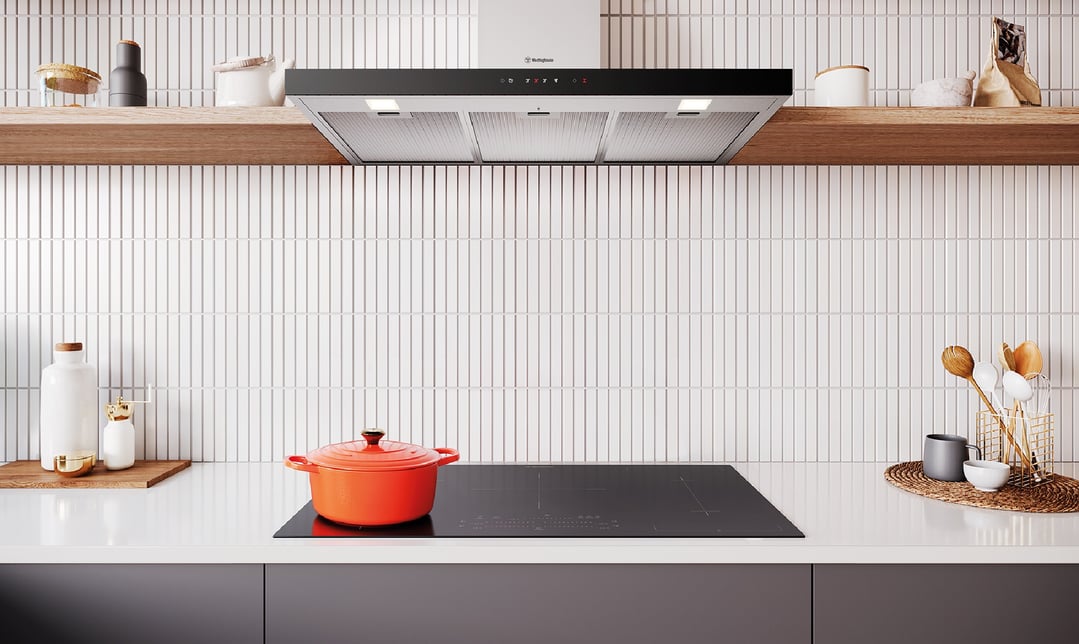 Canopy rangehood installed above an induction cooktop with a red pot